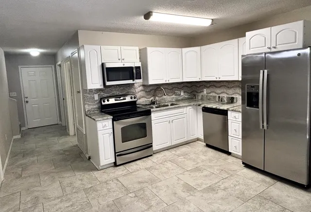 a kitchen with stainless steel appliances granite countertop a stove a refrigerator and a microwave