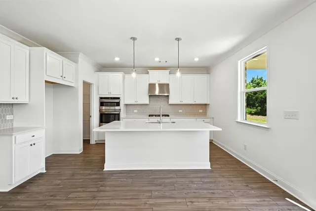 a view of kitchen with stainless steel appliances granite countertop a sink a stove a refrigerator and island with wooden floor