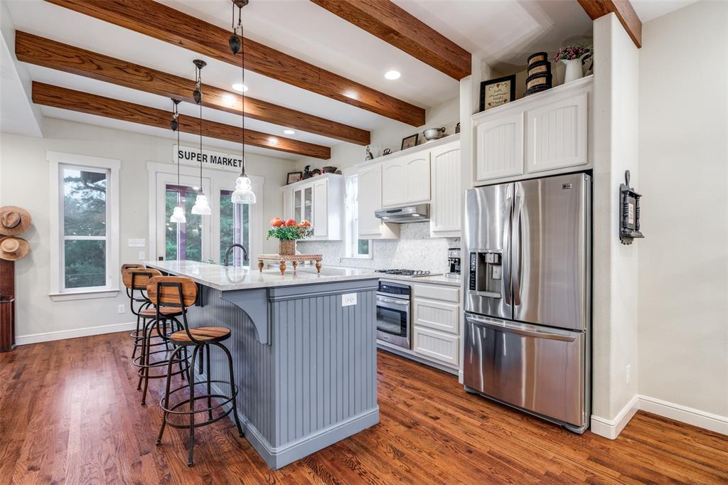 322 Red Maple Road Gunter, TX 75058 - Photo 10 of 33 a kitchen with stainless steel appliances a refrigerator a stove a sink dishwasher and a dining table with wooden floor