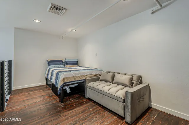 a bedroom with bed and wooden floor