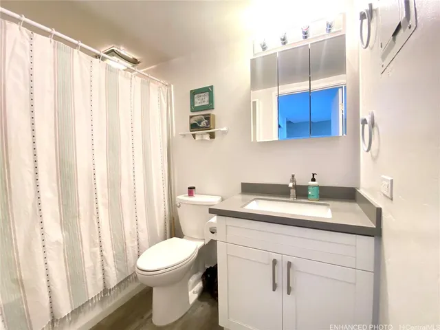 a bathroom with a granite countertop sink vanity mirror and a toilet