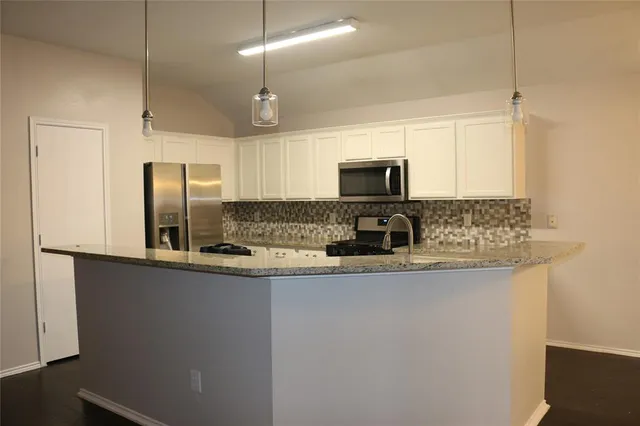 a kitchen with stainless steel appliances granite countertop a refrigerator a stove and a sink with wooden floor