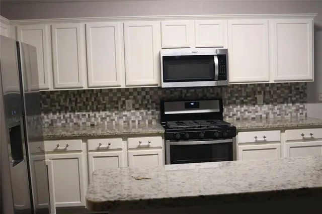 a kitchen with granite countertop white cabinets and a stove a oven with white countertops