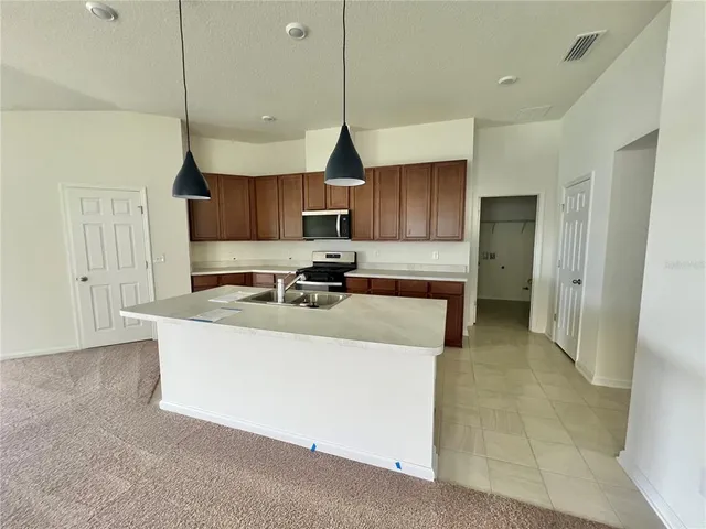 a kitchen with stainless steel appliances granite countertop a sink a stove a refrigerator and cabinets