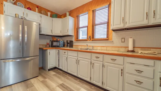 a kitchen with white cabinets and refrigerator
