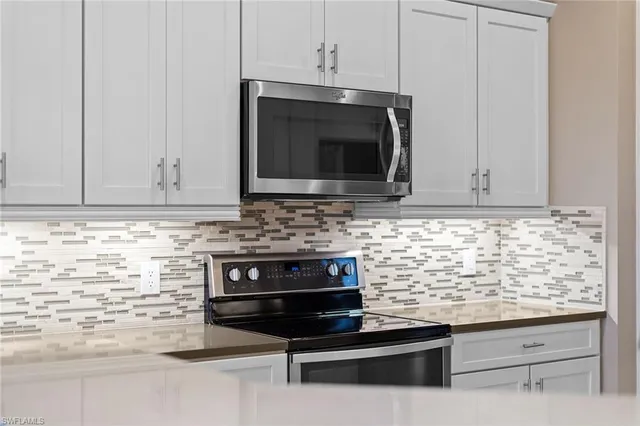 a kitchen with granite countertop white cabinets and stainless steel appliances