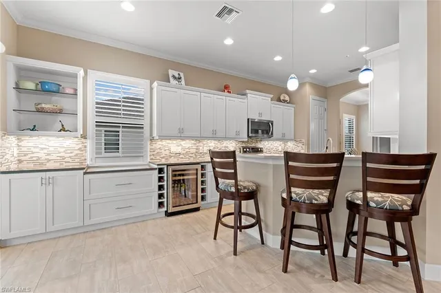a kitchen with stainless steel appliances kitchen island granite countertop a table chairs sink and cabinets