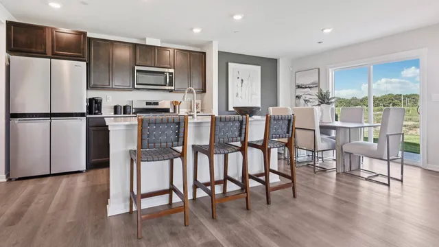 a kitchen with stainless steel appliances granite countertop a refrigerator a stove a microwave oven with a dining table and chairs with wooden floor