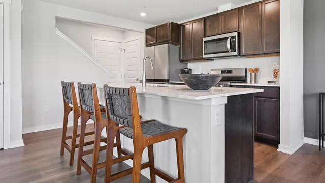 a kitchen with stainless steel appliances kitchen island a table chairs microwave and sink