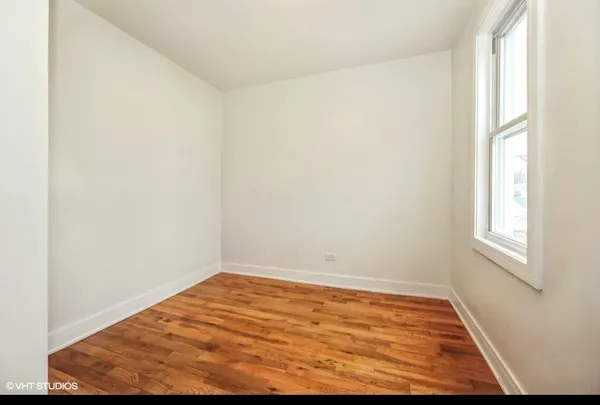 an empty room with wooden floor and window