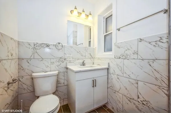 a bathroom with a granite countertop toilet sink and mirror