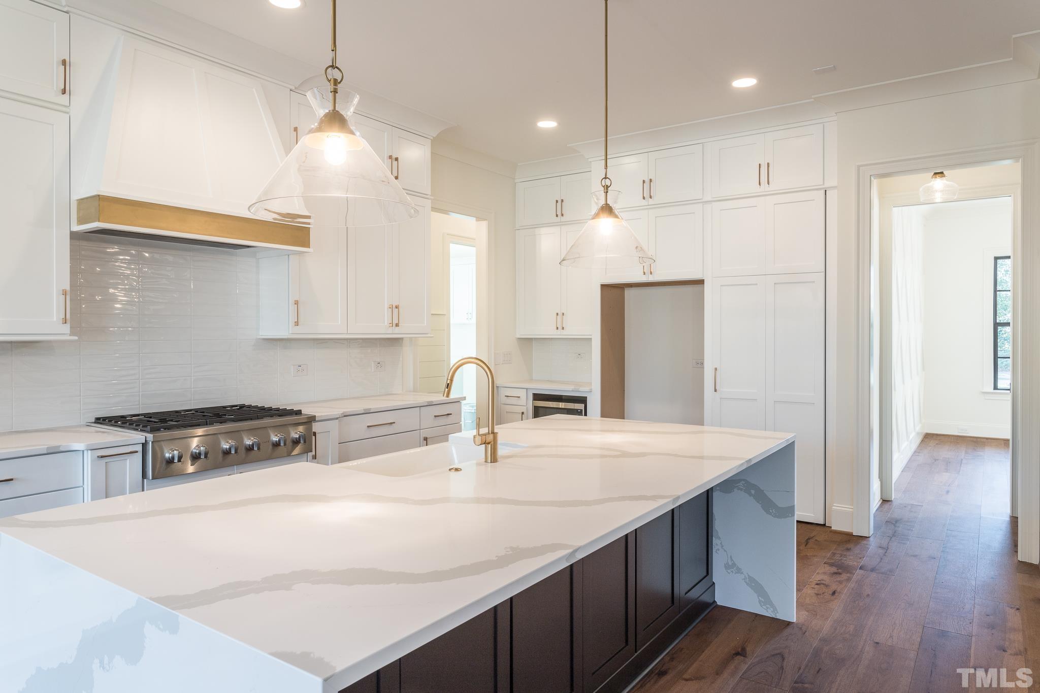 3820 Noremac Drive Raleigh, NC 27612 - Photo 11 of 46 a kitchen with kitchen island a sink a stove a refrigerator and chairs with wooden floor