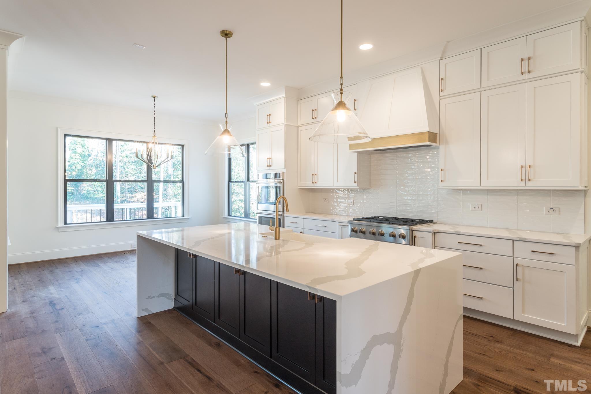 3820 Noremac Drive Raleigh, NC 27612 - Photo 17 of 46 a kitchen with a stove a sink a center island and wooden floor