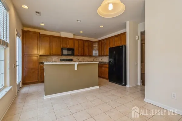 a kitchen with kitchen island granite countertop cabinets and refrigerator