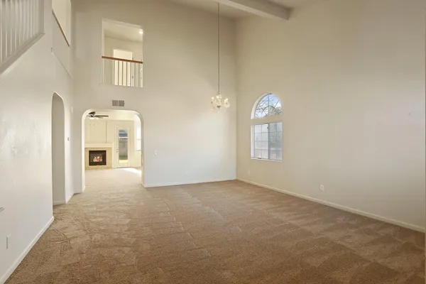 an empty room with chandelier fan and wooden floor