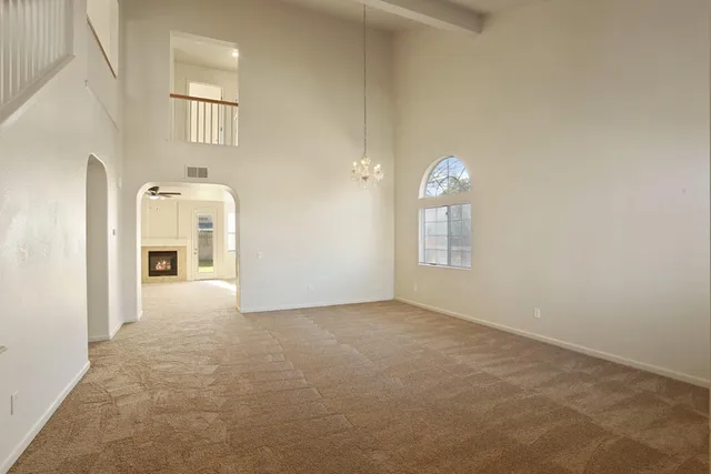 an empty room with chandelier fan and wooden floor
