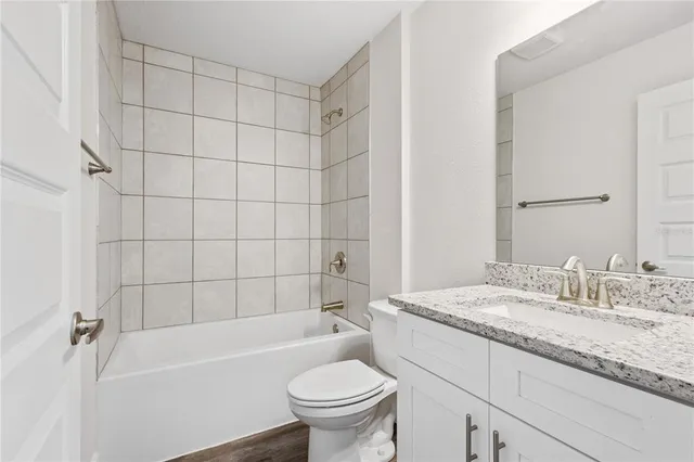a bathroom with a granite countertop sink a toilet and bathtub