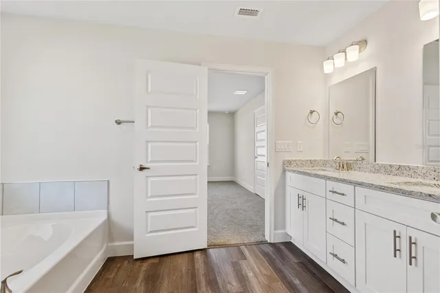 a spacious bathroom with a granite countertop sink a mirror and a bathtub