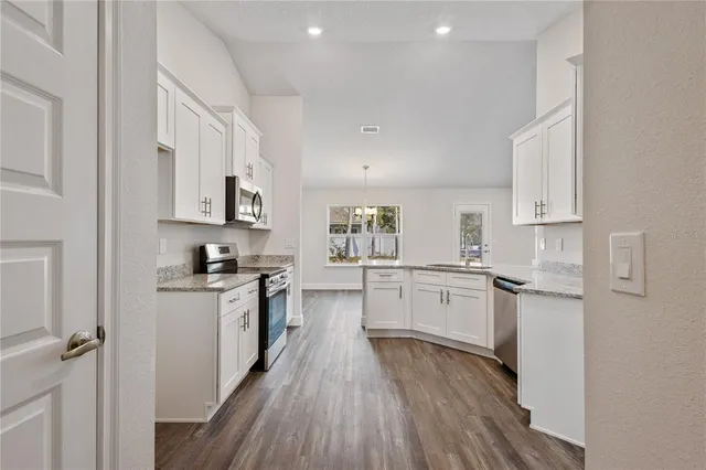 a kitchen with white cabinets stainless steel appliances a sink and a refrigerator