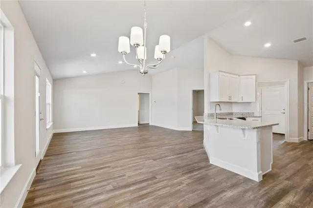 a kitchen with stainless steel appliances granite countertop a sink cabinets and wooden floor