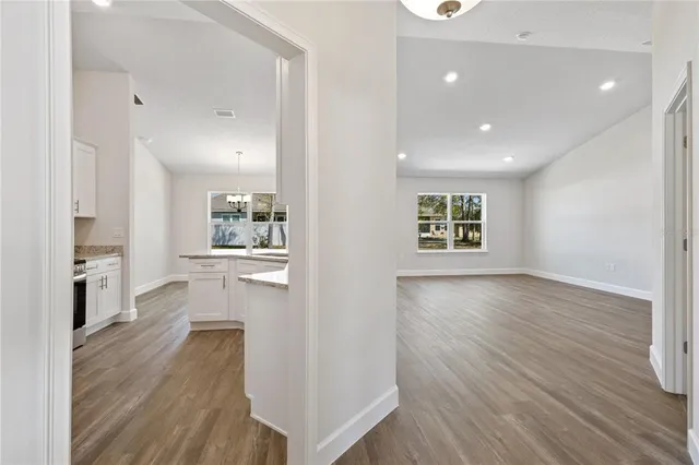 an empty room with wooden floor and a kitchen