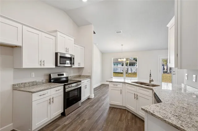 a kitchen with granite countertop a sink a stove and cabinets