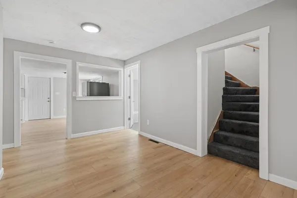 a view of an empty room with wooden floor and stairs