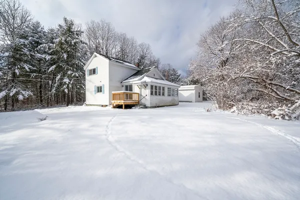 a view of house with yard and trees in the background