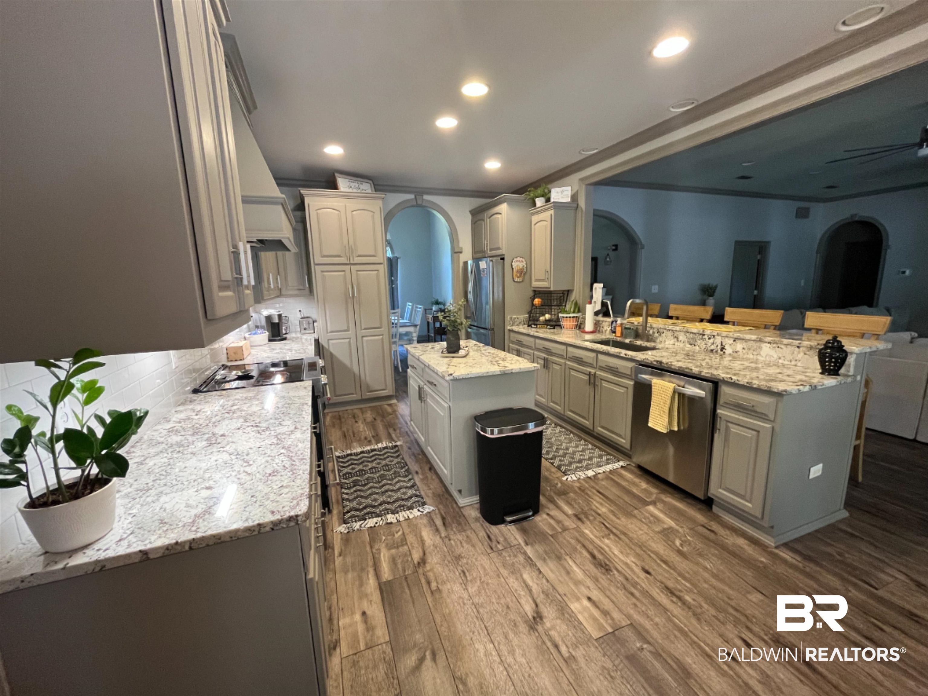 14316 Timber Ridge Drive Loxley, AL 36551 - Photo 6 of 23 Kitchen with arched walkways, a peninsula, dark wood finished floors, gray cabinetry, and backsplash