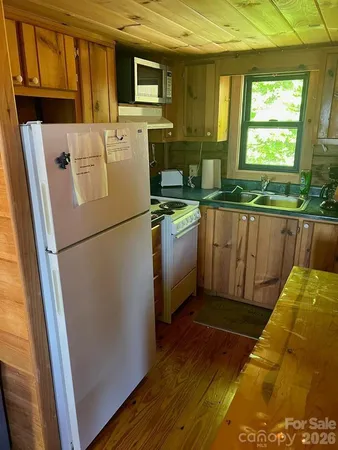 a kitchen with stainless steel appliances granite countertop a refrigerator a sink a stove a microwave oven with cabinets and wooden floor