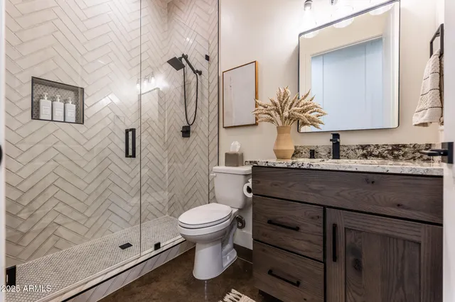 a bathroom with a granite countertop sink toilet mirror and shower