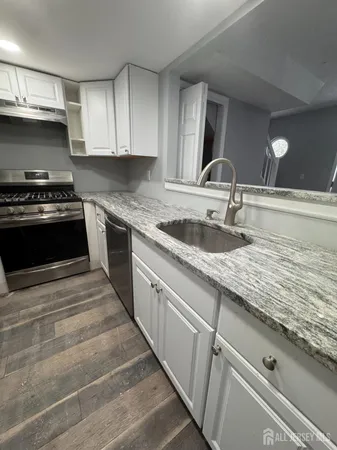 a kitchen with granite countertop a sink stove and cabinets