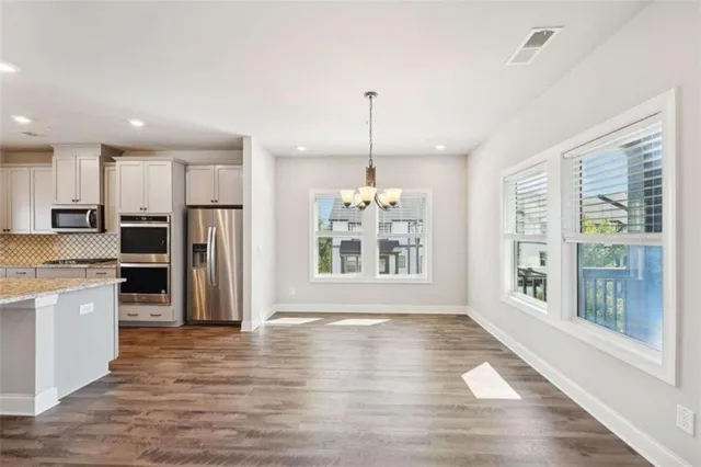 a kitchen with stainless steel appliances granite countertop a refrigerator a sink dishwasher a stove and a refrigerator with wooden floor