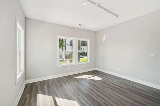 an empty room with wooden floor and windows