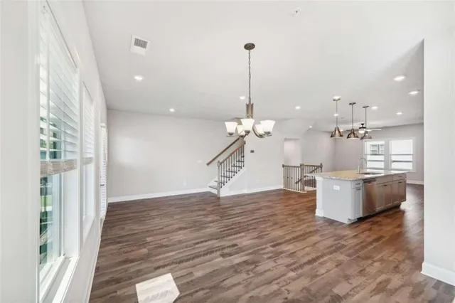 a room with kitchen island a wooden floor and a chandelier