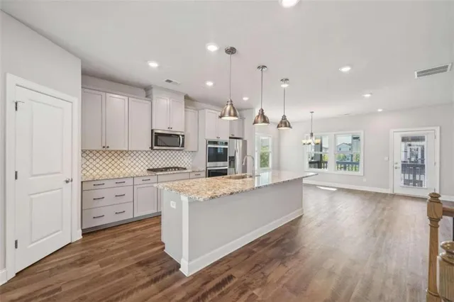 a large kitchen with granite countertop a large counter top stainless steel appliances and cabinets