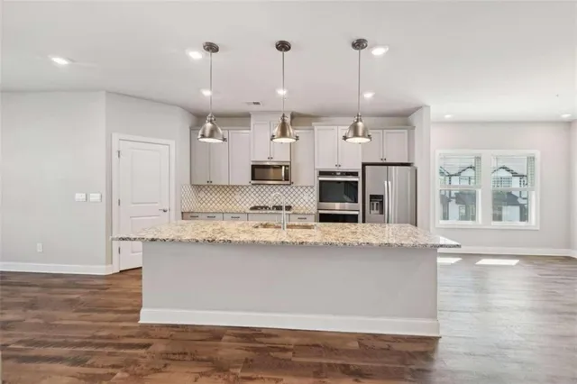 a large kitchen with granite countertop a large counter top and stainless steel appliances