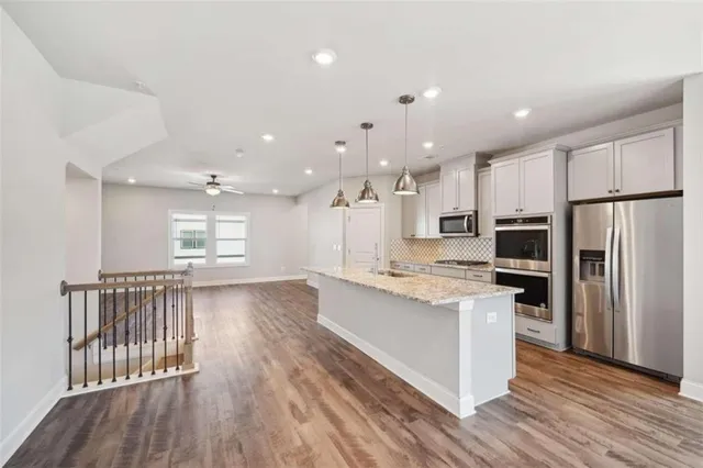a open kitchen with kitchen island a stove a refrigerator cabinets and wooden floor