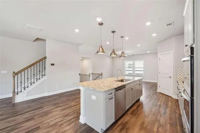 a large kitchen with stainless steel appliances kitchen island a large counter top and a wooden floor