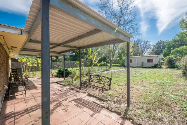 a view of a porch with wooden floor next to a yard