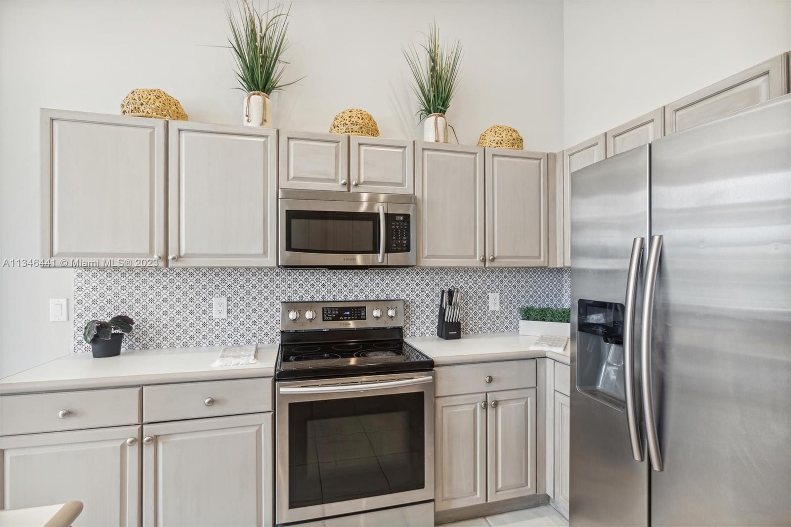 2883 Oakbrook Drive Weston, FL 33332 - Photo 46 of 74 a kitchen with stainless steel appliances a sink a refrigerator a stove a microwave and cabinets