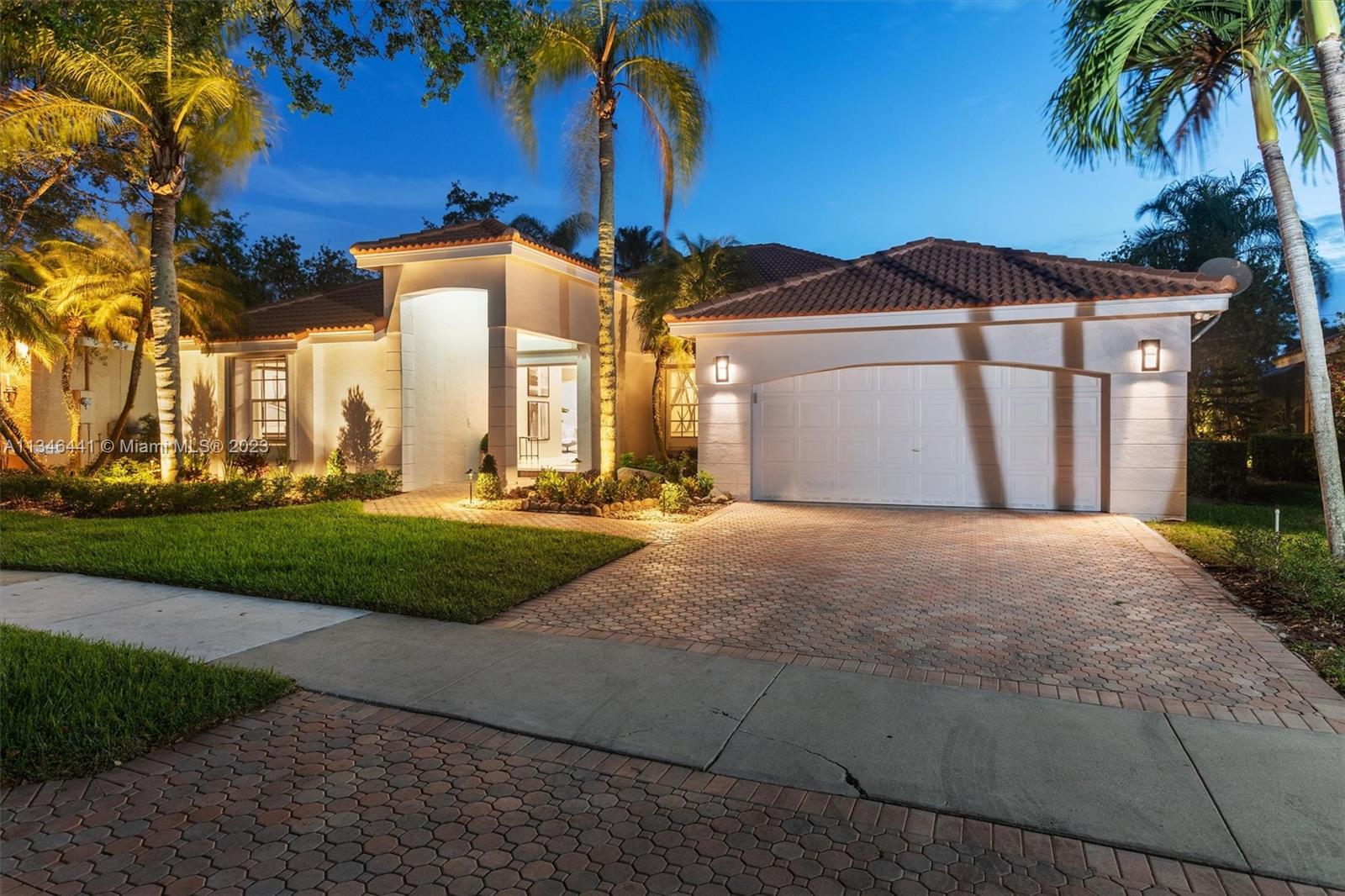 2883 Oakbrook Drive Weston, FL 33332 - Photo 8 of 74 a front view of a house with a yard and garage