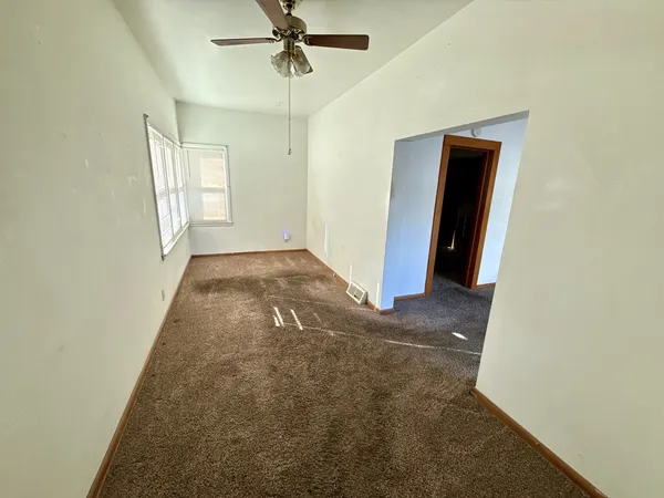 an empty room with windows and fan