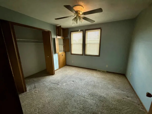 an empty room with windows and fan