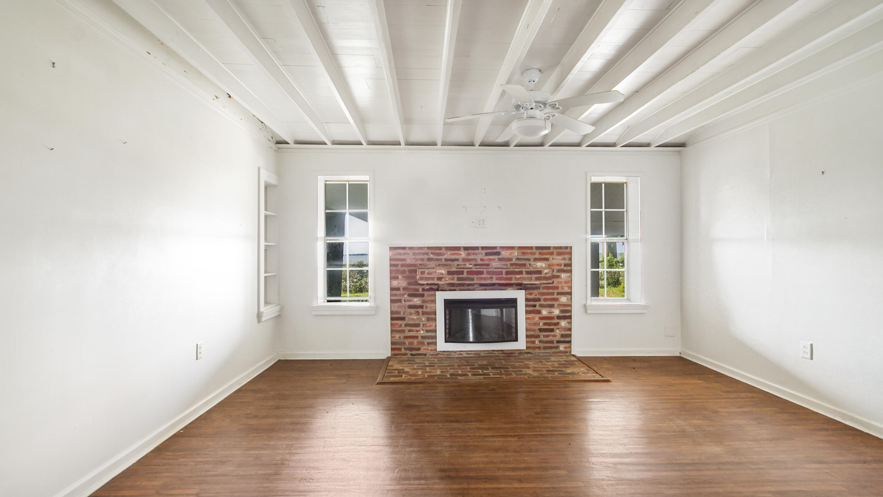 13636 Highway 20 Freeport, FL 32439 - Photo 14 of 42 an empty room with wooden floor fireplace and windows
