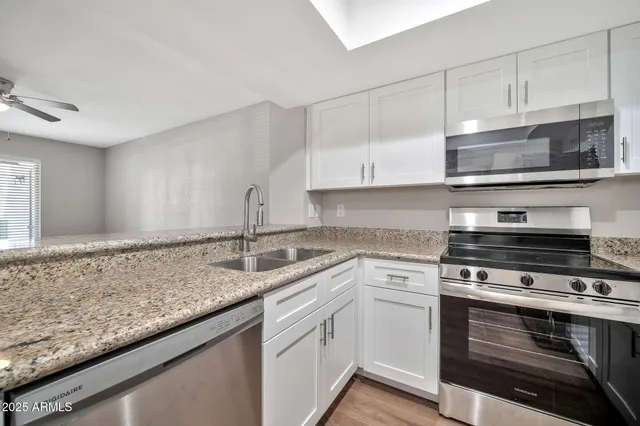 a kitchen with granite countertop a sink stainless steel appliances and cabinets