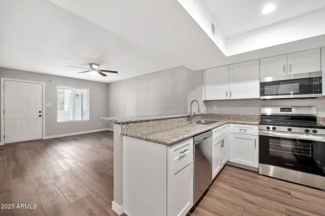 a kitchen with stainless steel appliances granite countertop a stove a sink and a refrigerator