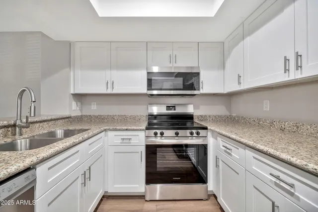 a kitchen with granite countertop white cabinets stainless steel appliances and a sink