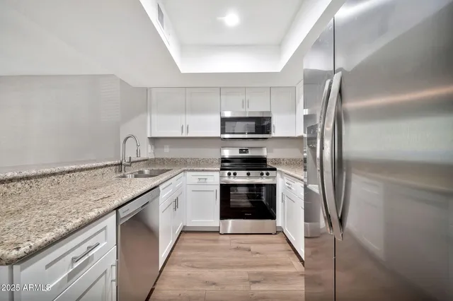 a kitchen with stainless steel appliances granite countertop a sink stove and refrigerator