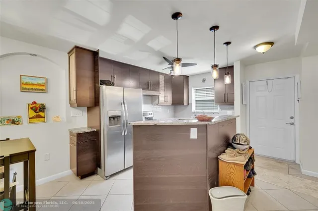 a kitchen with stainless steel appliances granite countertop a refrigerator a sink dishwasher a oven a dining table and chairs with wooden floor